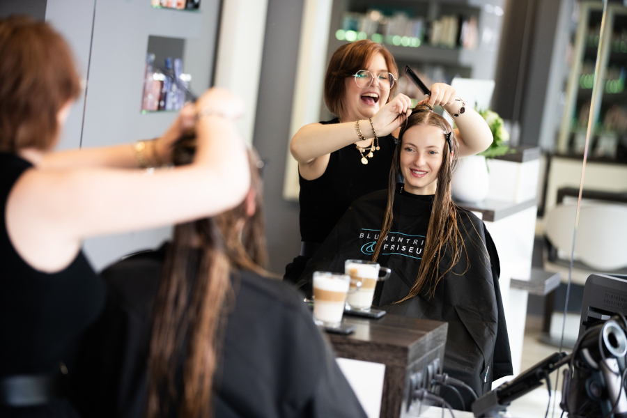 Schneiden Stylistin Jeanne Emmerich schneidet einer Kundin die Haare